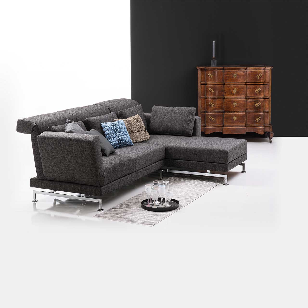 brühl moule small - Garnitur 73222 + 73231 Eckgarnitur in grauem Stoff mit Longchair links, dekoriert mit bunten Kissen. .