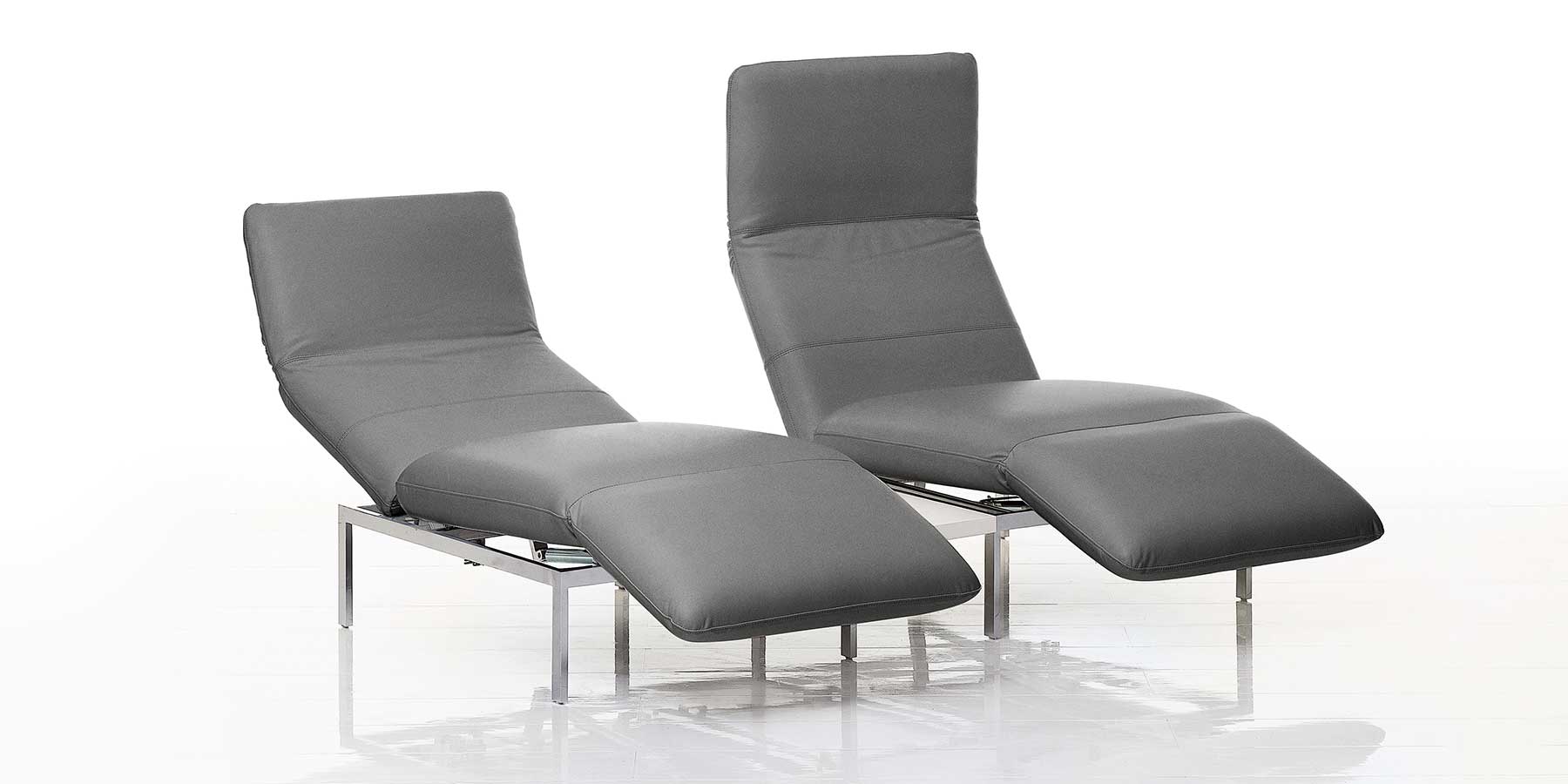 Kategorie roro small classic Zwei nebeneinander stehende Multifunktionssessel in grauem Leder. Beide sind zur Relaxposition aufgeschwenkt.