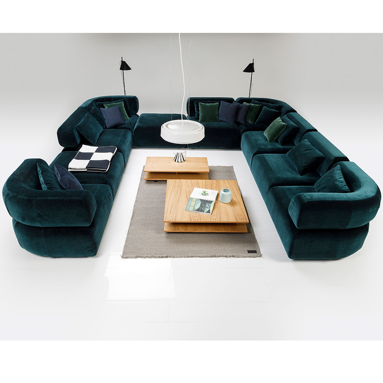 Tische all together U-förmige Sitzgarnitur in tiefgrünem Stoff mit zwei passenden Tischen in warmem Holz in der Mitte.