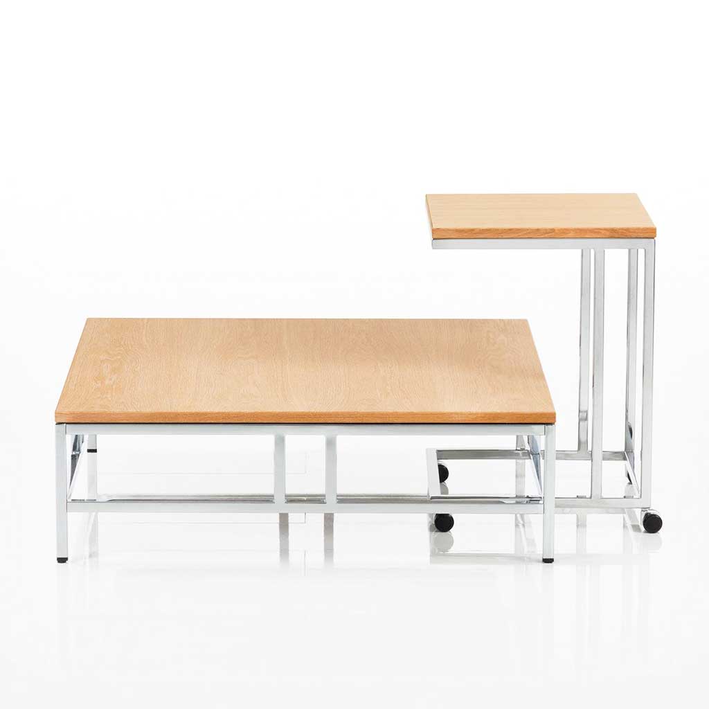 brühl easy pieces 62090 und 62091 Quadratischer Wohnzimmertisch mit Metall glänzendem Untergestell und Tischplatte in Buche. An den Wohnzimmertisch ist ein höherer Beistelltisch mit Rollen angestellt.