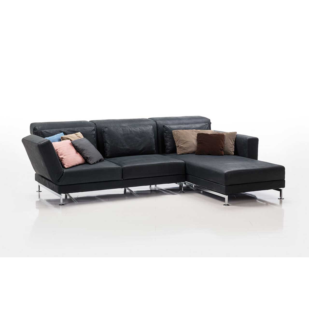 brühl moule-medium - Sitzgruppe 73131 + 73122 Eckgarnitur in schwarzem Leder mit Longchair rechts, dekoriert mit sehr vielen bunten Kissen.