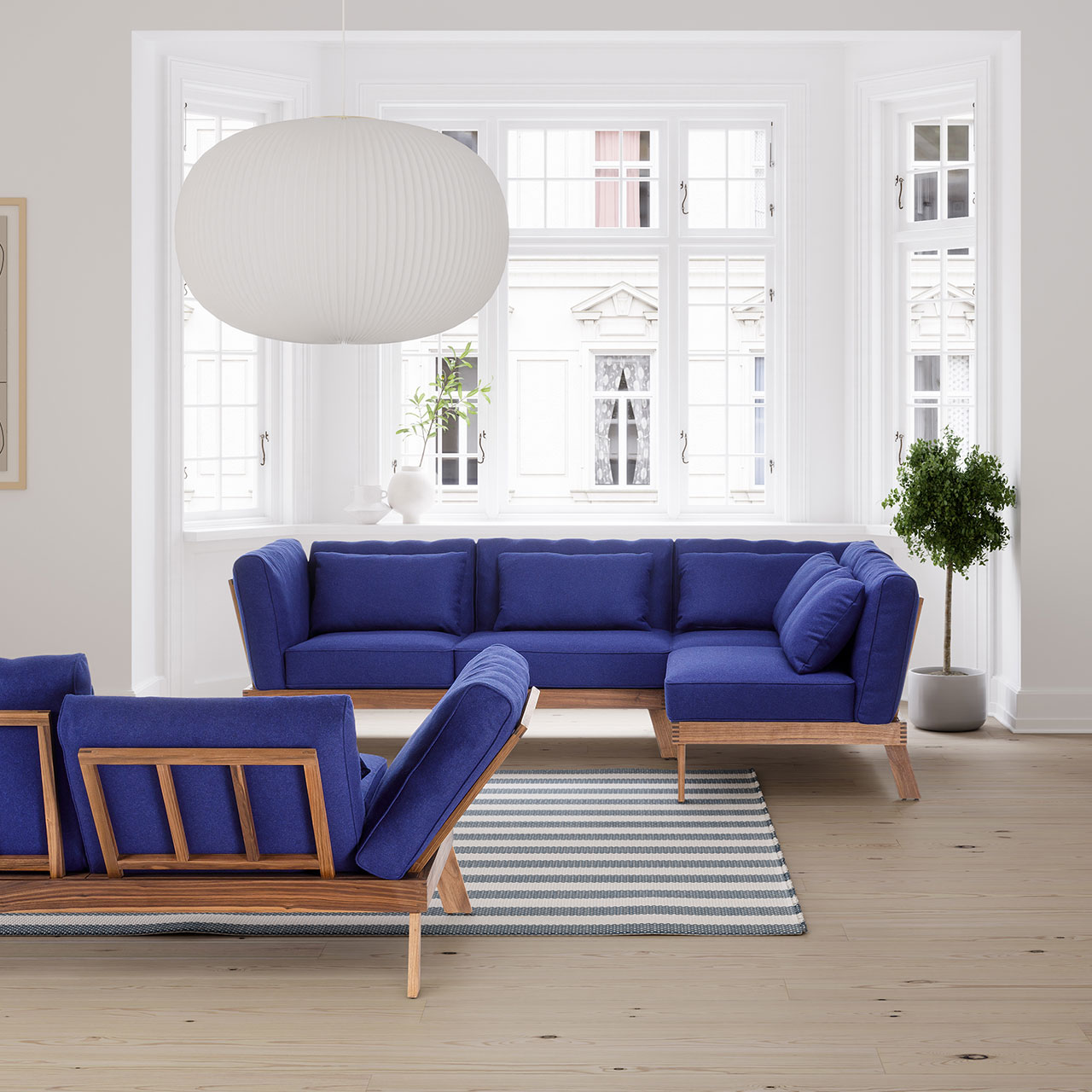 brühl lofoten pure - Garnitur 73521 + 73521 Ambientebild. Zwei Eckgarnituren der Serie brühl lofoten pure mit Untergestell aus heller Eiche und Polstern in königsblau vor einem breiten Altbaufenster.