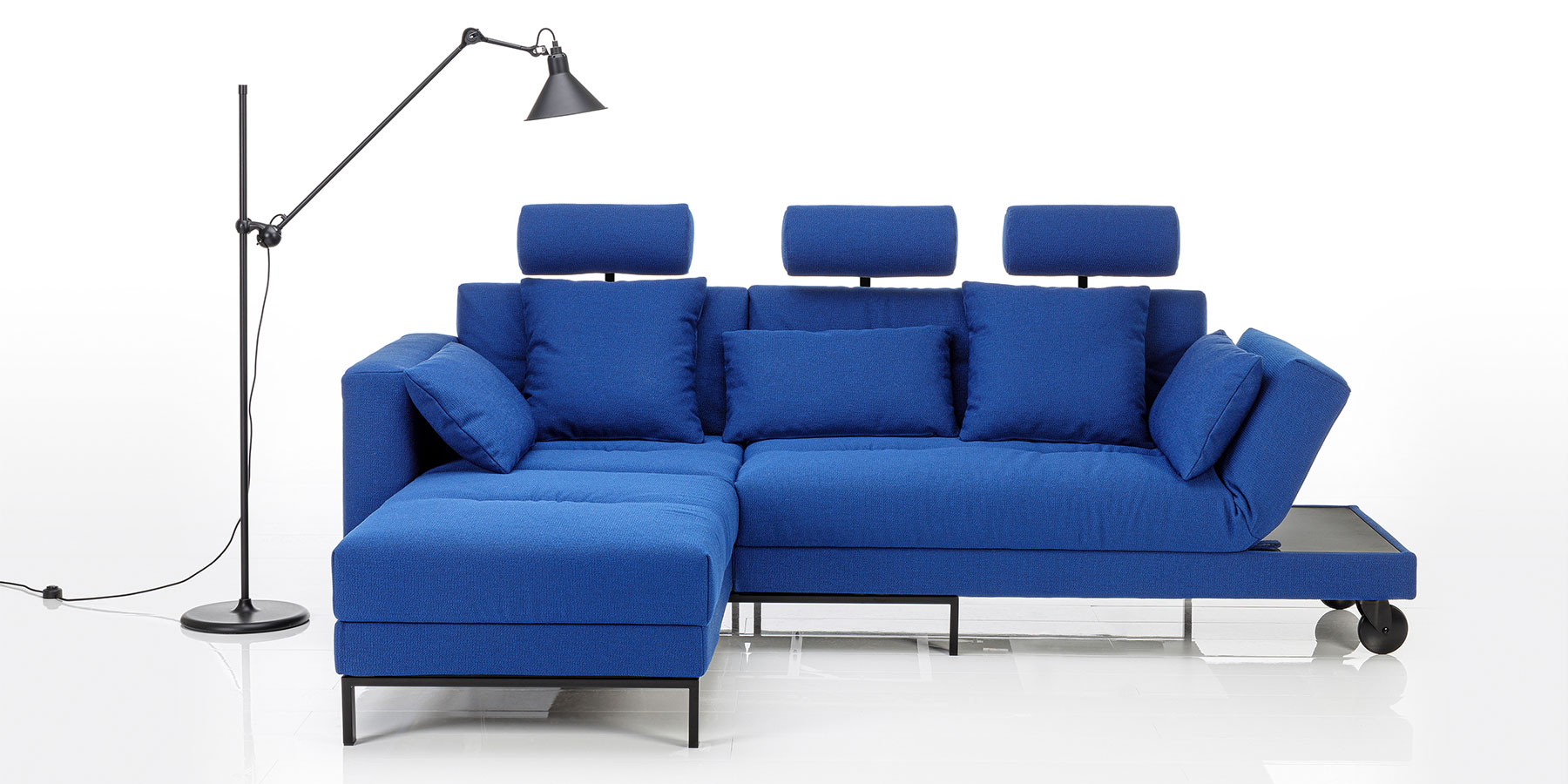 Multifunktionssofa four-two soft Eine blaue Eckgarnitur aus einem Longchair und einem Anstellsofa. An allen Sitzplätzen ist eine Kopfstütze montiert.