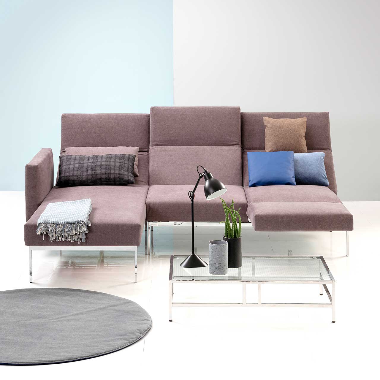 Garnitur brühl roro medium soft 74022 + 74007. Ambientebild Ambientebild der Eckgarnitur der Serie roro medium soft mit Longchair links und Anstellsofa rechts in Stoff. Die Rückenlehnen sind aufgefaltet und zur Relaxposition abgesenkt, die Armlehne rechts ist zur Fußstütze umgeschwenkt.