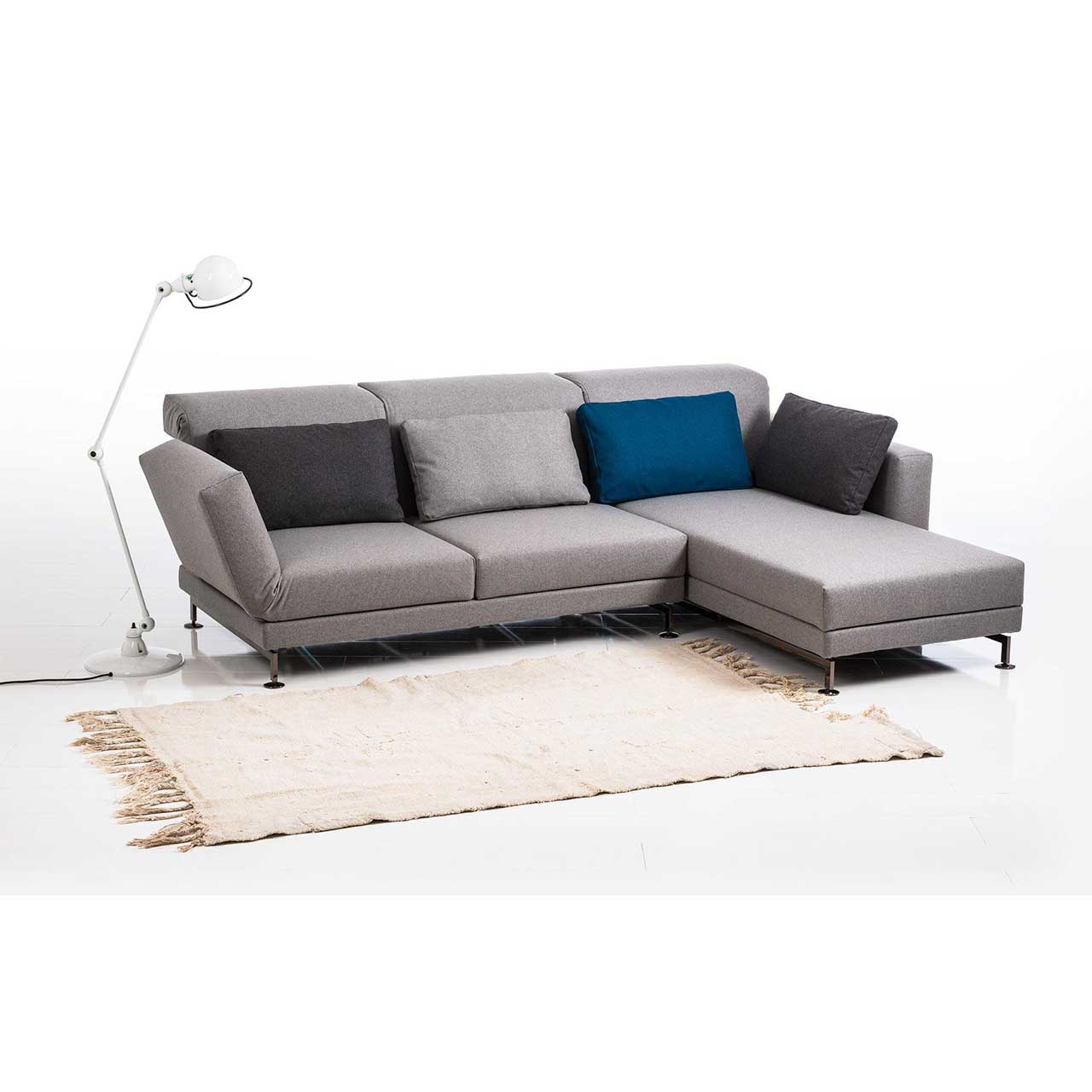brühl moule small - Garnitur 73222 + 73231 Eckgarnitur in grauem Stoff mit Longchair rechts, dekoriert mit vier Kissen in dunkelgrau, blau und hellgrau.