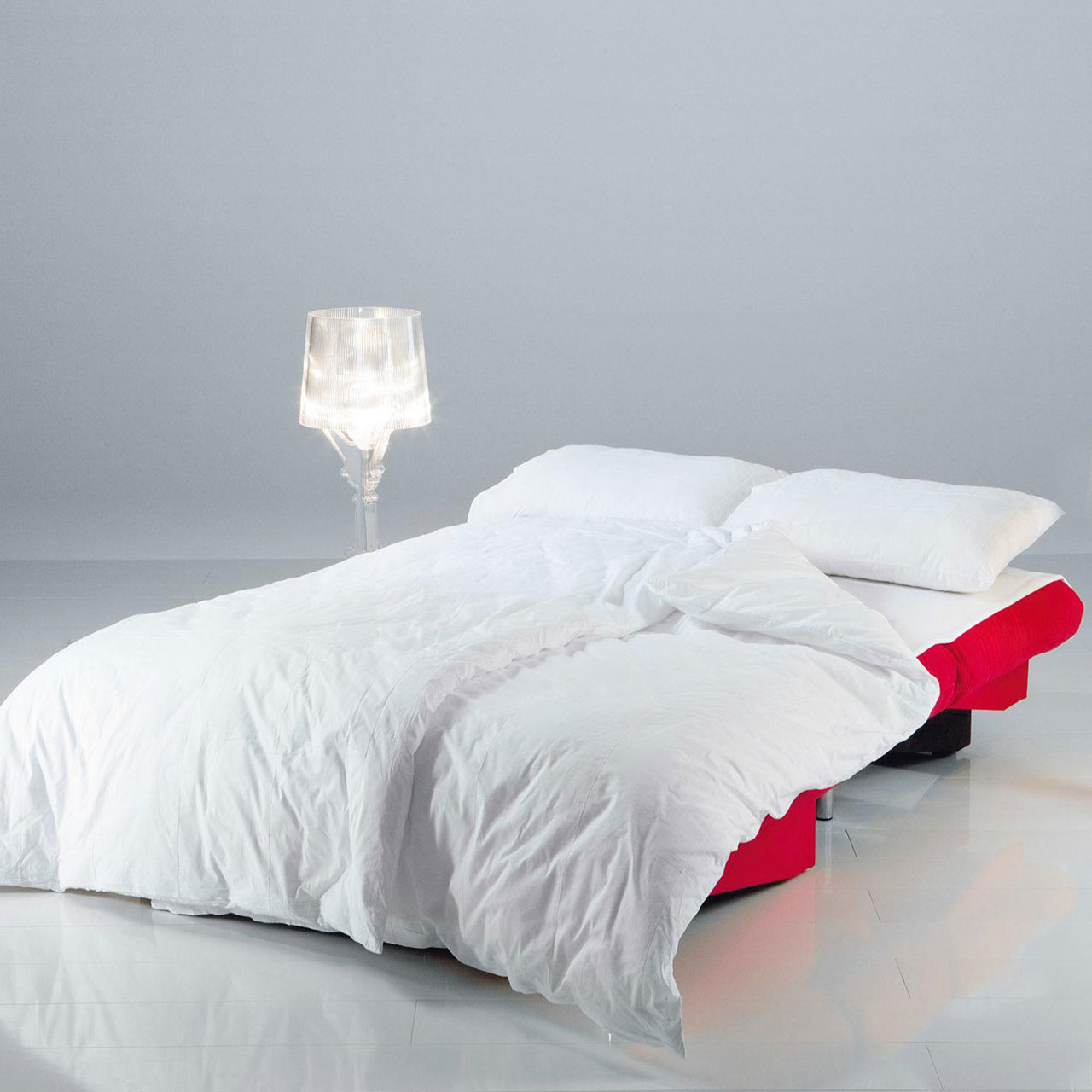 brühl quint 31616 / 31617 Ein rotes, zu einer Liegefläche umgebautes Bettsofa. Auf dem Sofa liegt weiß bezogenes Bettzeug.