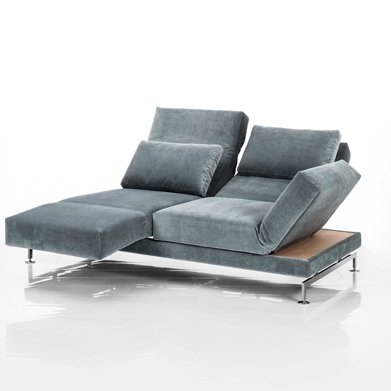 brühl moule small - Sofa 73207 Graues Sofa. Rechts und links neben den Armlehnen befinden sich schmale Ablageflächen in hellem Holz. Die linke Armlehne ist als Fußstütze vorgeschwenkt, die Rückenlehne leicht abgesenkt.