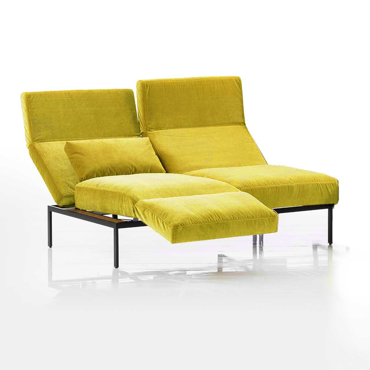 Das Anstellsofa der Serie roro medium spring mit zwei Sitzplätzen in gelbem Stoff. Die Rücken sind leicht abgesenkt, die Armlehne auf der linken Seite ist als Fußstütze vorgeschwenkt.
