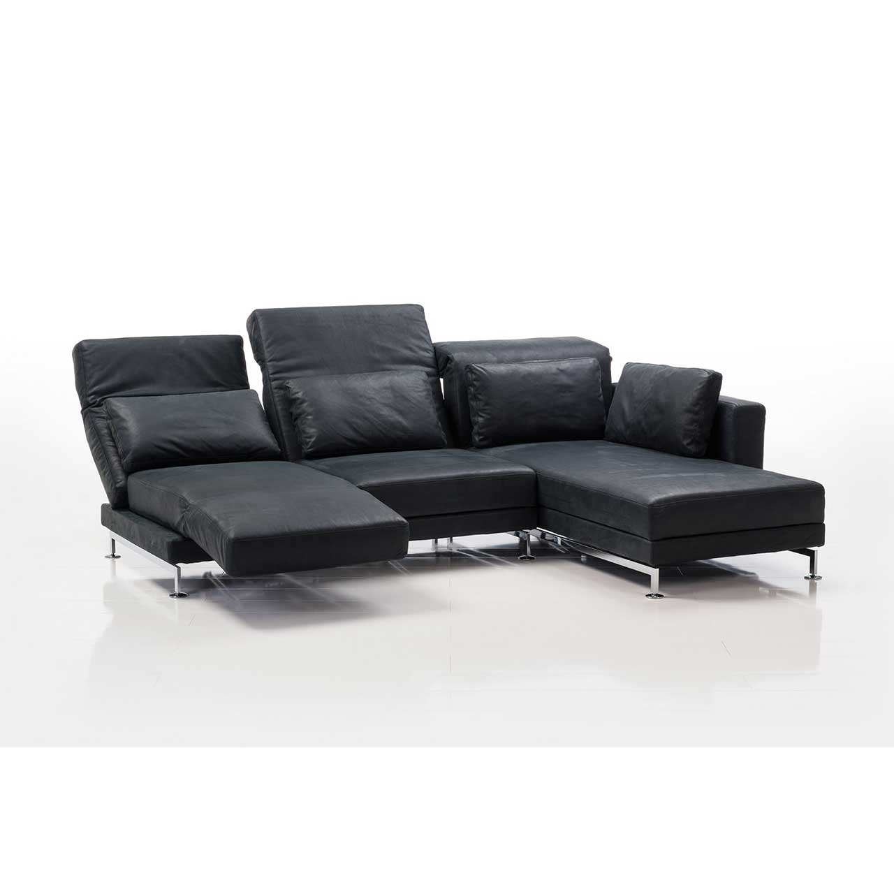 brühl moule small - Garnitur 73222 + 73231 Eckgarnitur in schwarzem Leder mit Longchair rechts, dekoriert mit vier Kissen. Der Sitzplatz ganz links ist zur Relaxliege umgebaut.