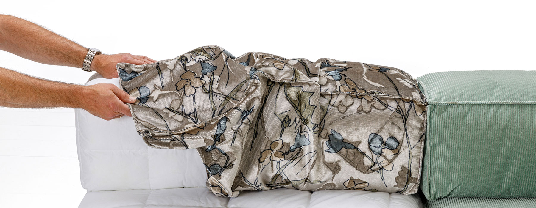 Pflegehinweise brühl Polstermöbel Zwei Männerhände beziehen ein  kubisch geformtes Rückenpolster mit einem neuen Bezug.