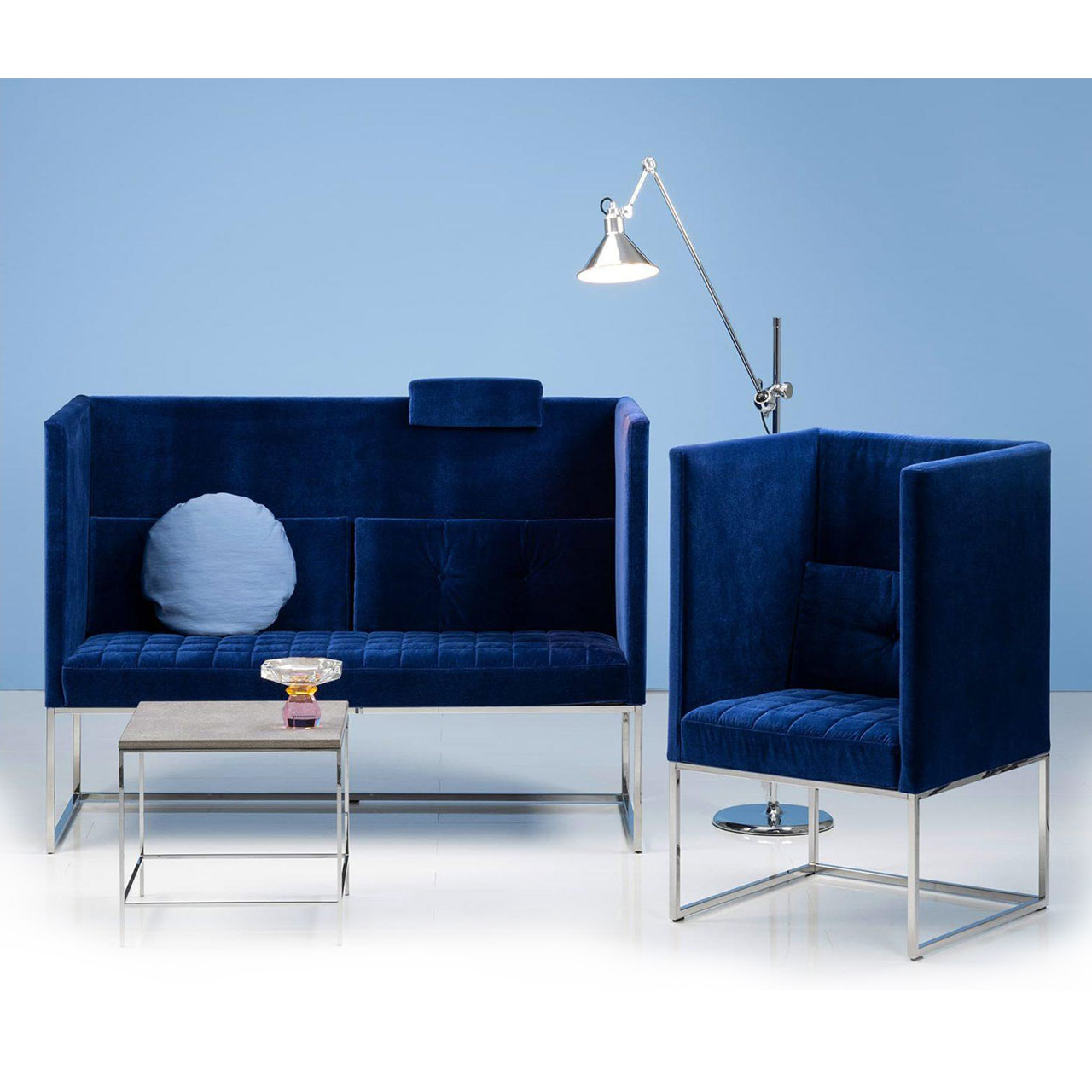 brühl belami high Ambiente Ambientebild: Eine blaue Polsterbank mit passendem Sessel stehen vor einer hellblauen Wand. Die Seiten und Rücken der Möbel sind hoch.
