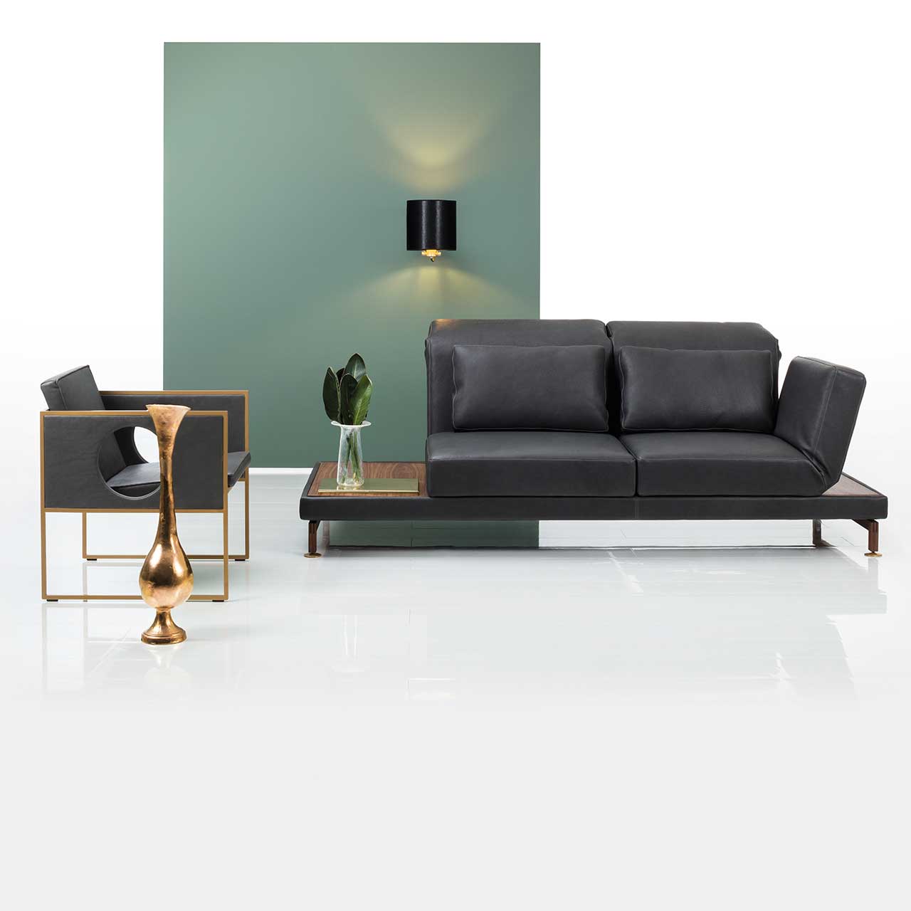 brühl moule-medium - Anstellsofa 73129 2-Sitzer Milieu Ambientebild: Anstellsofa in schwarzem Leder mit Armlehne links und Abstellflächen rechts und rechts. Links des Sofas steht ein Sessel der Serie grace.