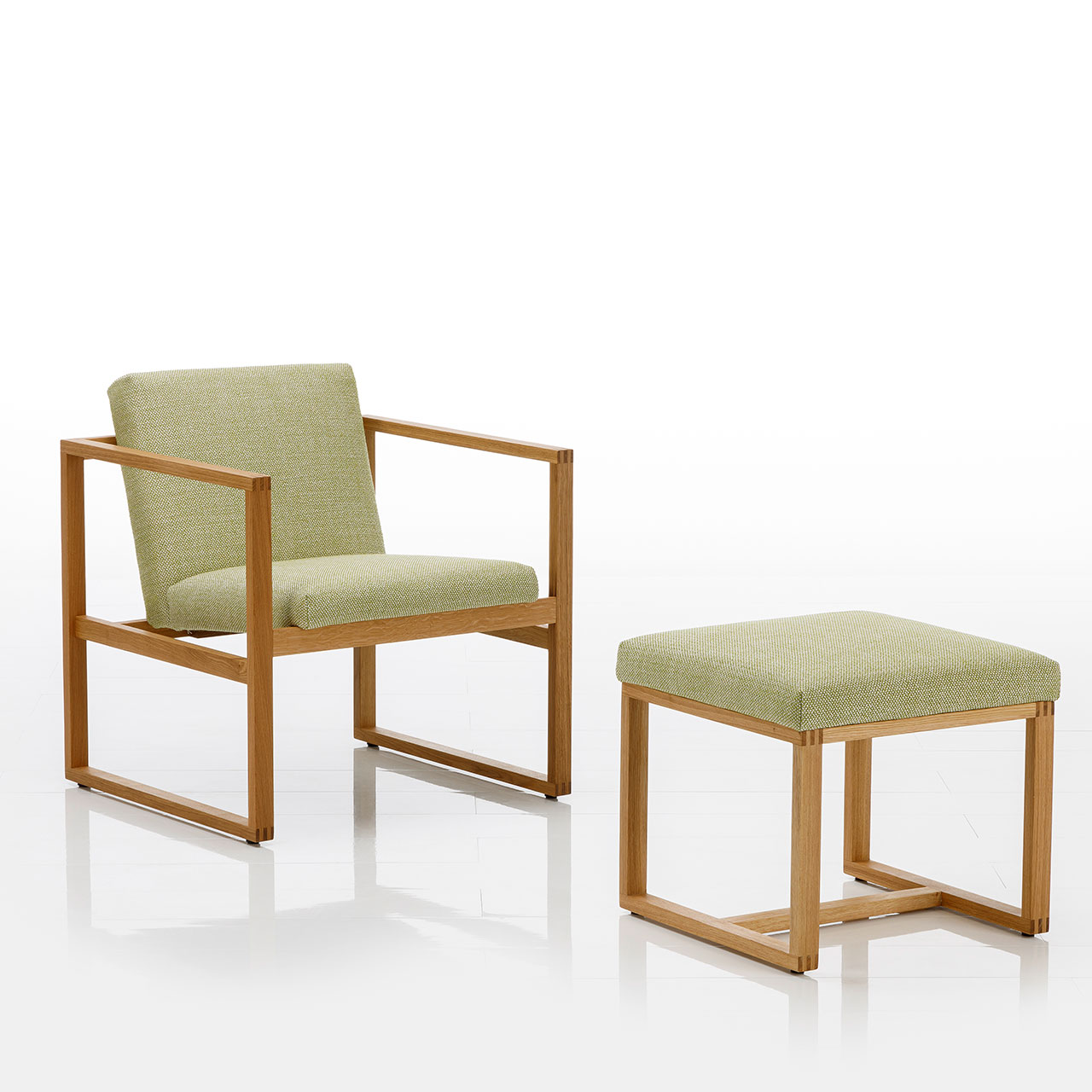 brühl grace wood Sessel und Hocker Ein Sessel mit niedriger Rückenlehne und ein passender Hocker. Beide Möbel sind mit einem limettengrünen Stoff bezogen. Die Untergestelle sind aus einem warmen Holz.