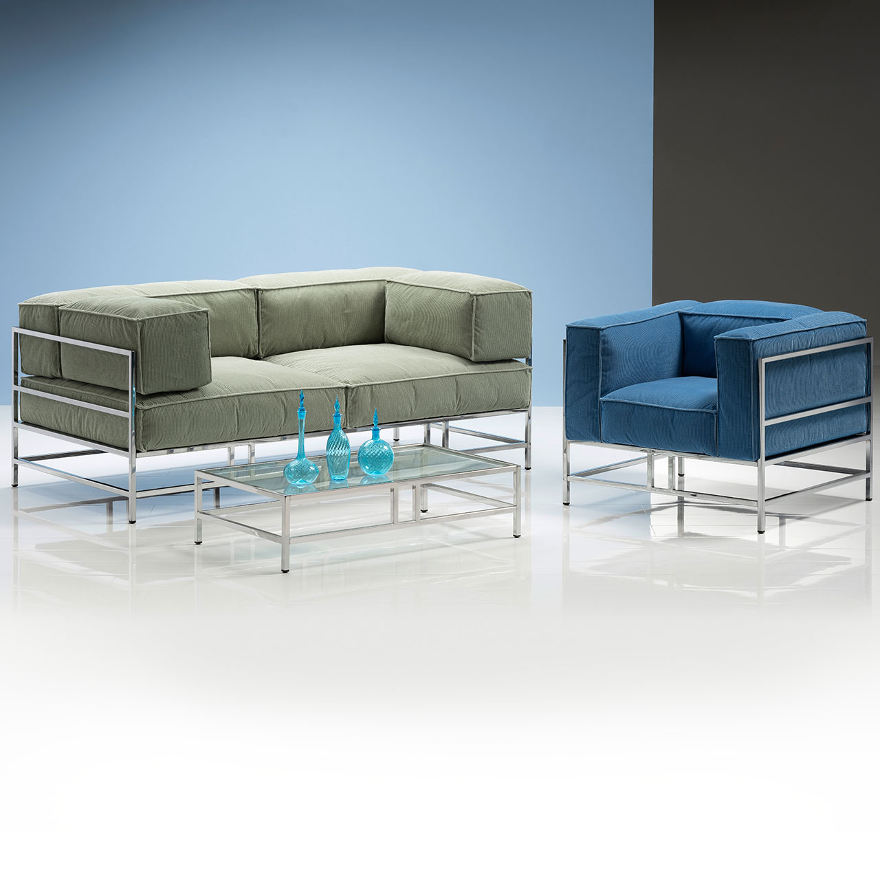 brühl easy pieces Sessel Sessel mit hellblauen Polstern und mit chrom glänzendem Untergestell. Links davon steht ein Sofa mit hellgrünen Polstern und ebenfalls chrom glänzenden Untergestell.