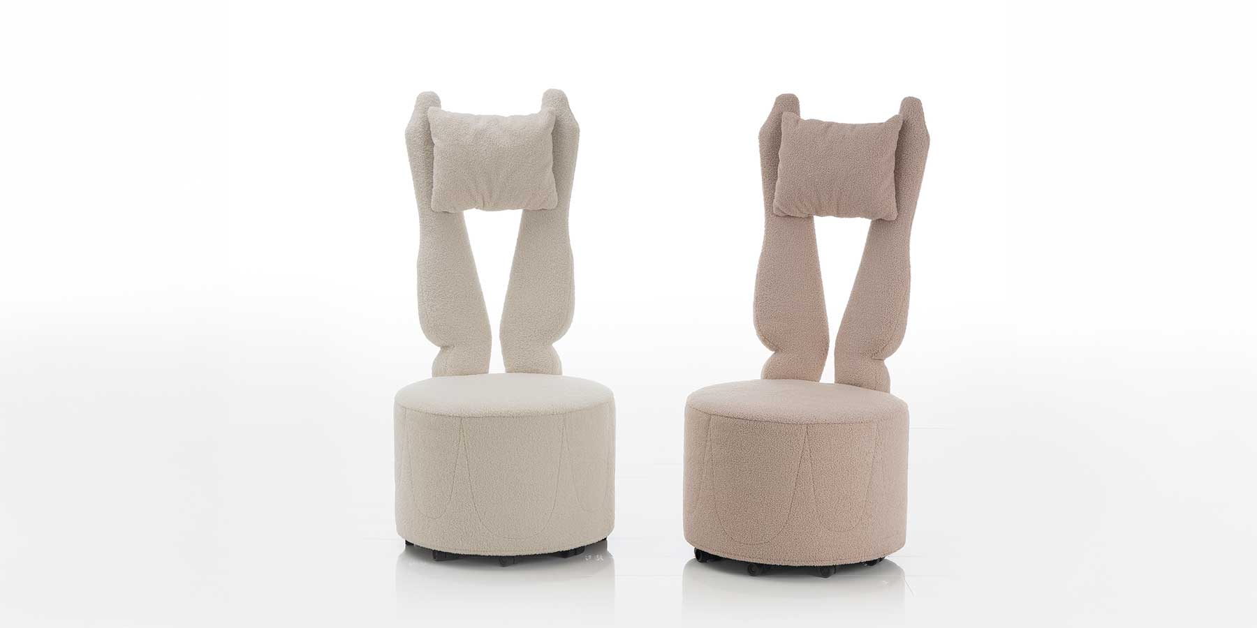 libellule Highbackchairs von brühl Zwei Hochlehnsessel mit runder Sitzbasis und gegabelter Rückenlehne. Der linke Sessel ist in einem cremeweißen Stoff, der rechte in einen pastellrosa Stoff bezogen.