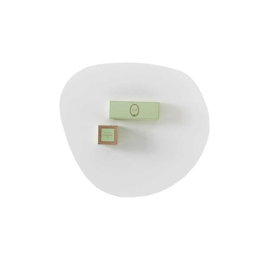 brühl mosspink - Tisch medium 56292 Sicht auf eine weiße, ungleichmäßig rund geformte Tischplatte. Darauf liegen zwei hellgrüne, rechteckige Gegenstände.