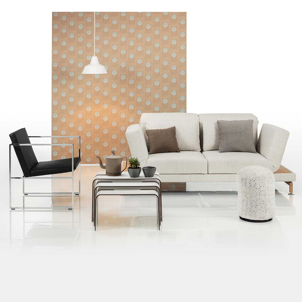 brühl moule small - Sofa 73207 Ambientebild. Sofa der Serie brühl moule in weißem Stoff, rechts davor ein runder Hocker. Vorne links steht ein Sessel der Serie grace mit schwarzem Lederbezug.