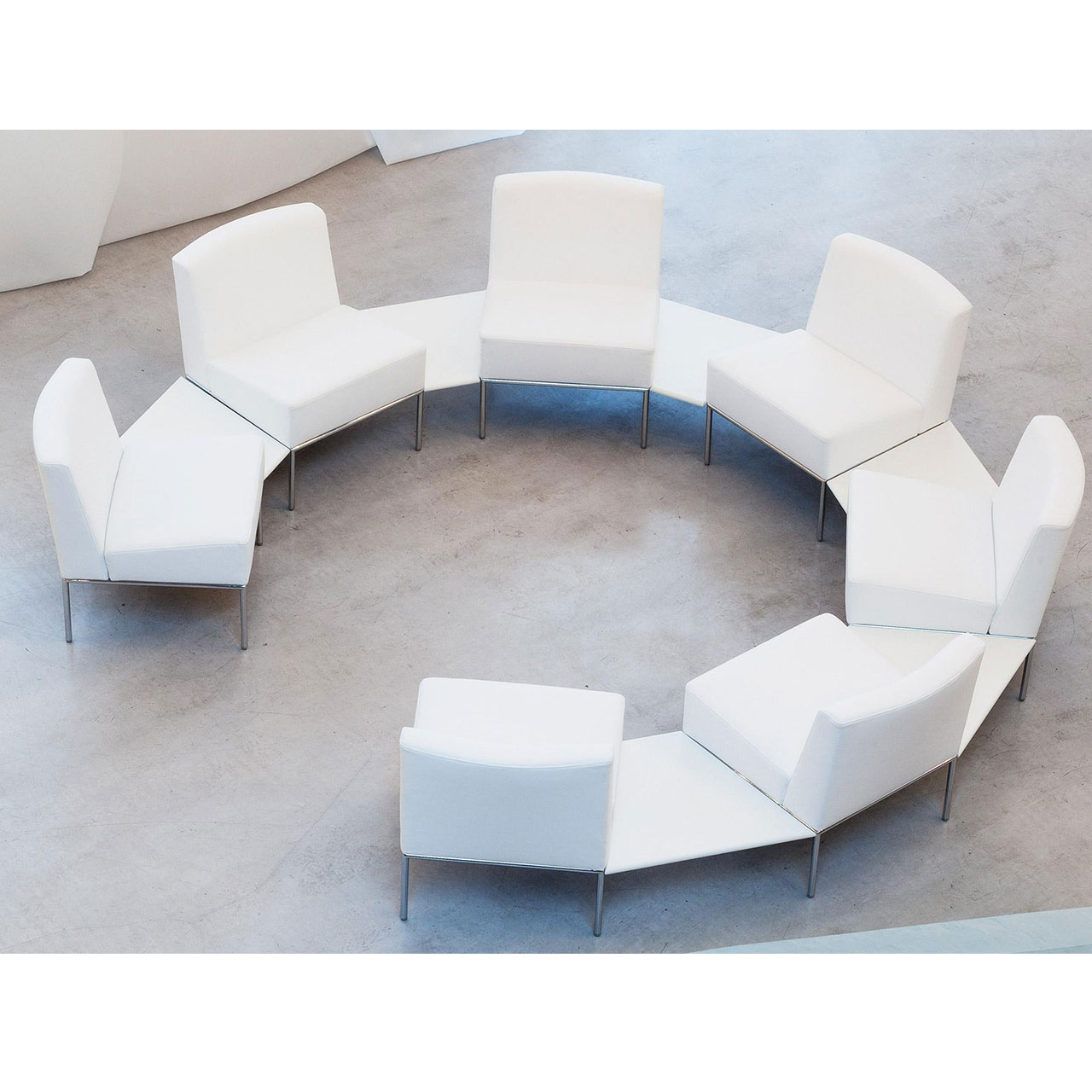brühl add1 Sitzgruppe Ambiente Kreisförmige Sitzgruppe aus sieben weißen Sesseln ohne Armlehnen. Diese sind durch weiße Einhängetische verbunden.