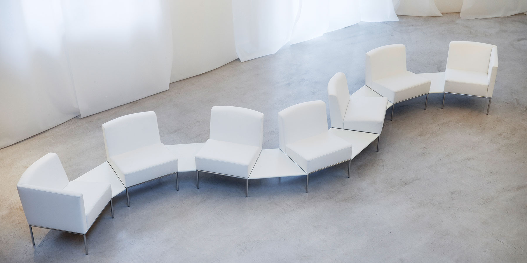 Flexible Sitzlösungen von brühl add1 Sieben weiße Sessel von brühl add1 sind mit Ablagen schlangenlinienförmig miteinander verbunden.